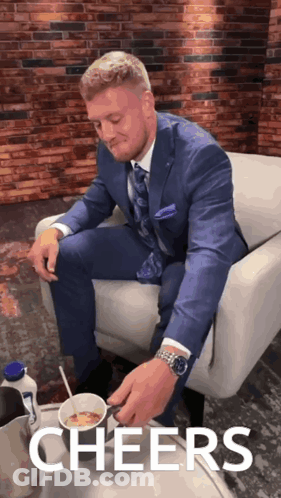 Man In Suit Sitting On Couch With Cereal Saying Cheers GIF