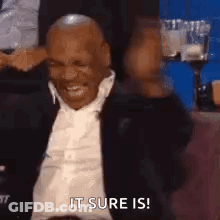 Man In Suit Sitting Smiling Hand To Head GIF