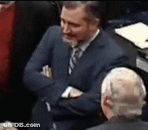Man In Suit Sitting With Arms Crossed In Crowd GIF