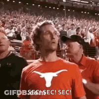 Man In Suit Sitting With Arms Crossed In Crowd GIF