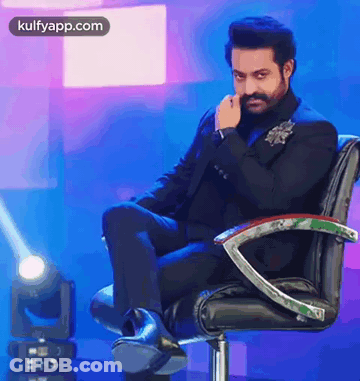 Man In Suit Sitting With Hand On Face GIF