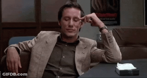 Man In Suit Sitting With Hands On Head GIF