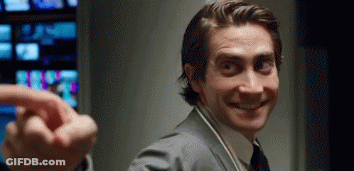 Man In Suit Smiling And Pointing At Camera With Headphones GIF
