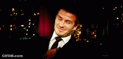 Man In Suit Smiling Before Red Curtain GIF
