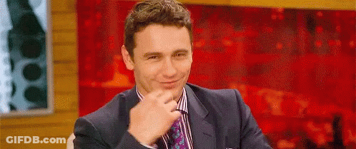Man In Suit Smiling Before Red Wall GIF