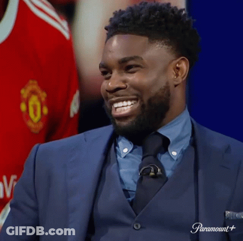 Man In Suit Smiling Beside Manchester United Shirt GIF