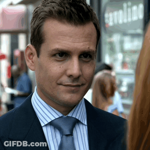 Man In Suit Smiling In Front Of Gasoline Sign GIF