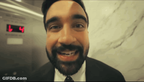 Man In Suit Smiling In Front Of L4 Display GIF