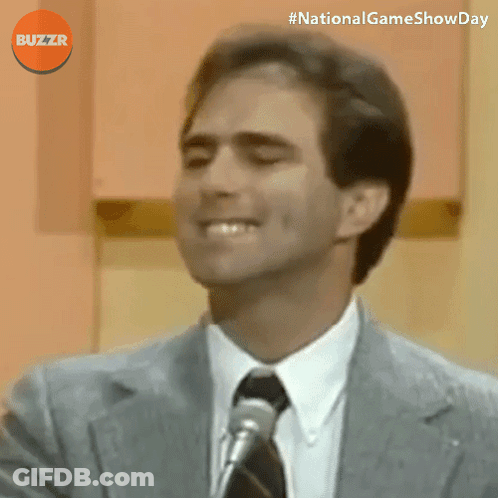 Man In Suit Smiling In Front Of Microphone With Buzzr Logo GIF