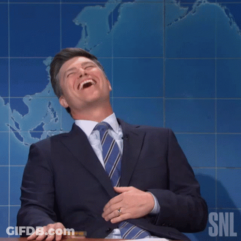 Man In Suit Smiling In Front Of SNL Logo GIF