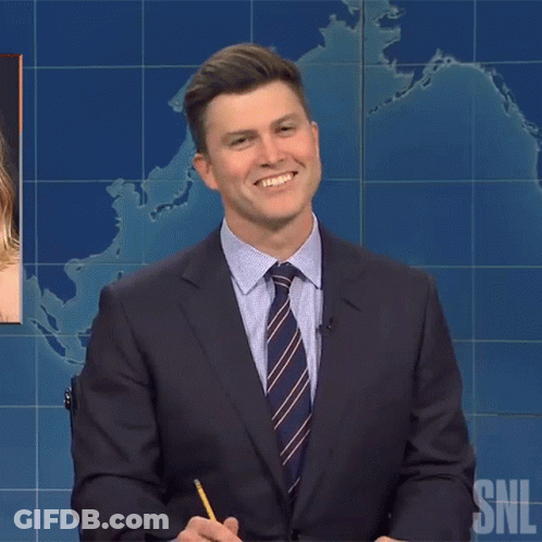 Man In Suit Smiling In Front Of SNL Sign GIF