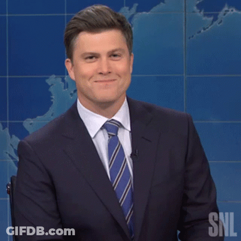 Man In Suit Smiling In Front Of SNL Sign GIF