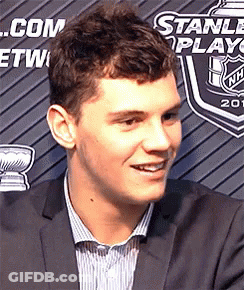 Man In Suit Smiling In Front Of Stanley Cup Banner GIF