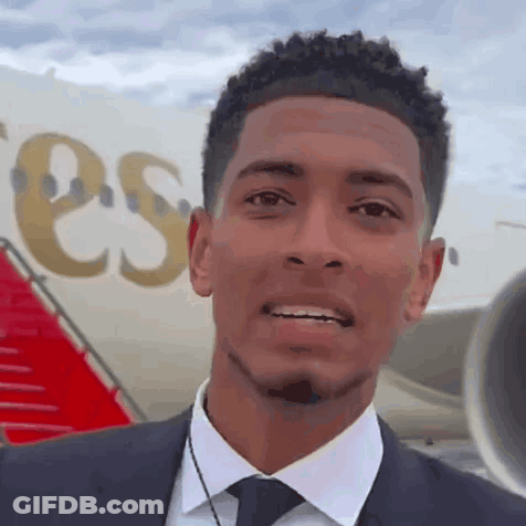 Man In Suit Smiling Next To Plane Saying ESS GIF