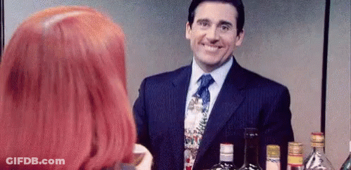 Man In Suit Smiling While Redhead Woman Holds Wine GIF