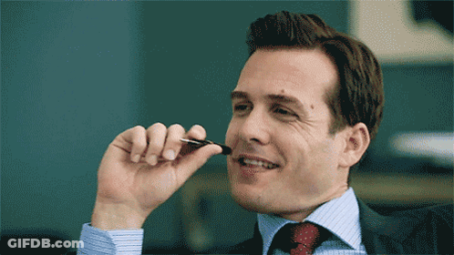 Man In Suit Smiling With Pen In Mouth GIF