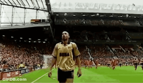 Man In Suit Speaking Into Microphone At Champions League Logo GIF