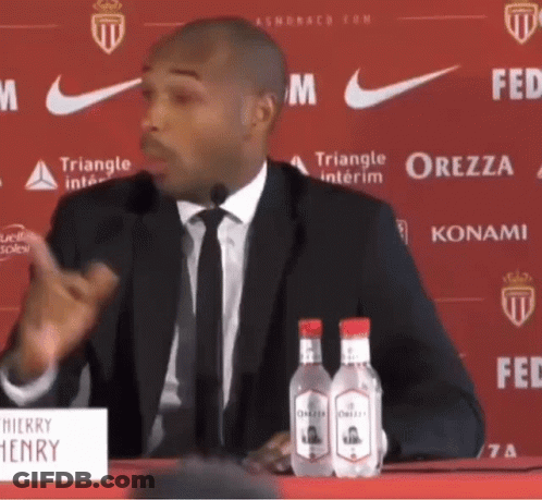 Man In Suit Speaking Into Microphone At Henry Sign GIF