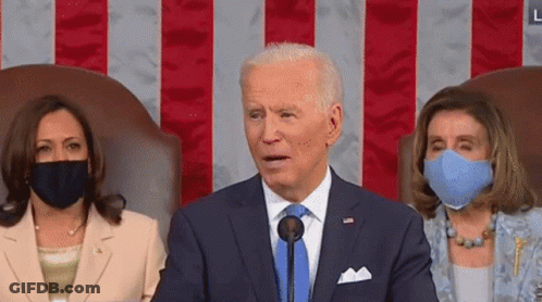 Man In Suit Speaking Into Microphone With Two Masked Women GIF