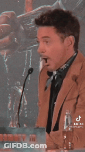 Man In Suit Standing At Microphone With Mouth Open GIF