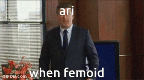 Man In Suit Standing At Window Saying Ari When Femoid GIF