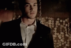 Man In Suit Standing Before Christmas Tree GIF
