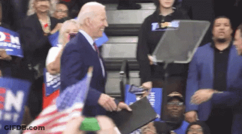 Man In Suit Standing Before Crowd With Signs GIF
