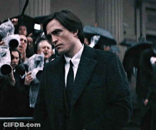 Man In Suit Standing Before Crowd With Umbrellas GIF