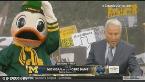 Man In Suit Standing Before Duck Mascot GIF