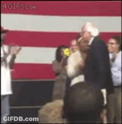 Man In Suit Standing Before Flag GIF