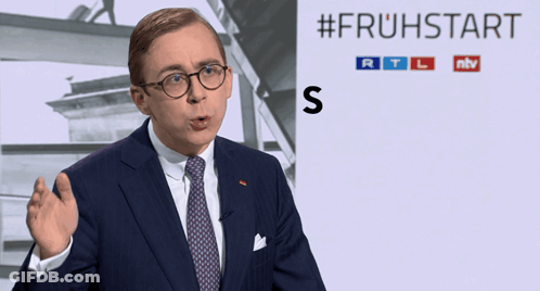 Man In Suit Standing Before #Fruhstart Sign GIF