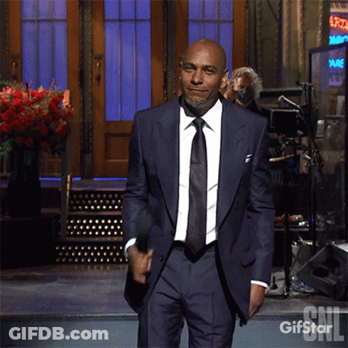 Man In Suit Standing Before Gifstar Sign GIF