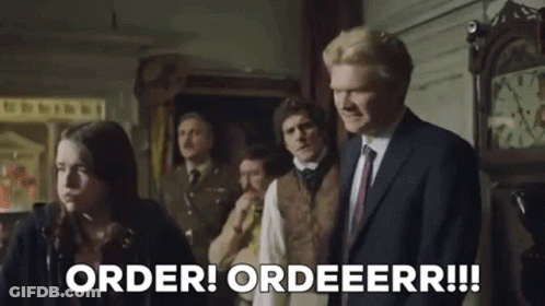 Man In Suit Standing Before Group And Clock GIF