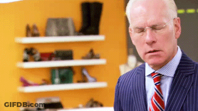 Man In Suit Standing Before Shoe Shelf GIF