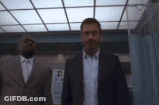 Man In Suit Standing Before Sign GIF