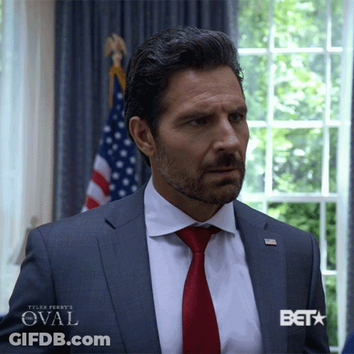 Man In Suit Standing Before Window With Beta GIF