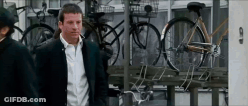 Man In Suit Standing In Front Of Bicycles GIF