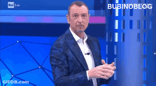 Man In Suit Standing In Front Of Blue Wall Saying Bubinoblog GIF