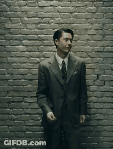 Man In Suit Standing In Front Of Brick Wall GIF