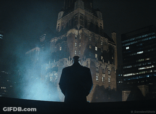 Man In Suit Standing In Front Of Building At Night GIF