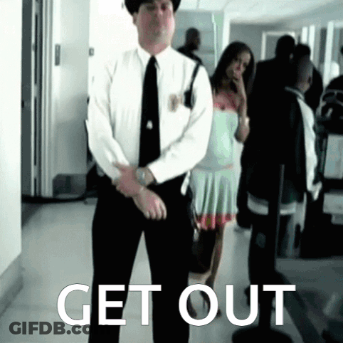 Man In Suit Standing In Front Of Get Out Sign GIF