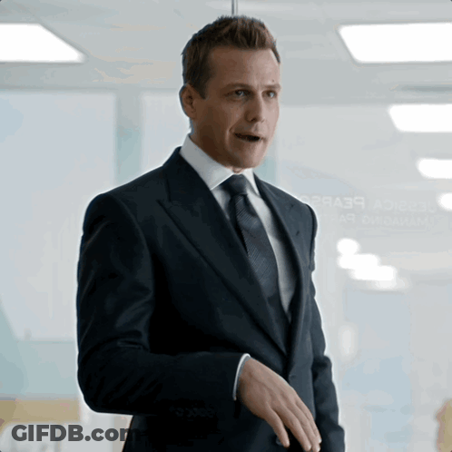 Man In Suit Standing In Front Of Glass Wall Saying A2b3r GIF