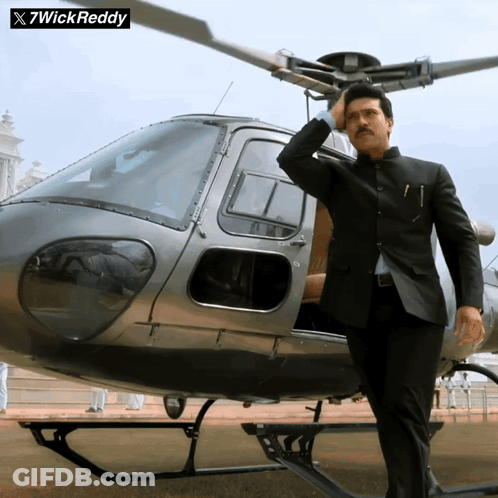 Man In Suit Standing In Front Of Helicopter With 7Wick Reddy GIF