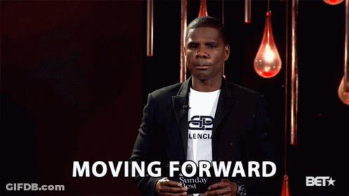 Man In Suit Standing In Front Of Moving Forward Sign GIF