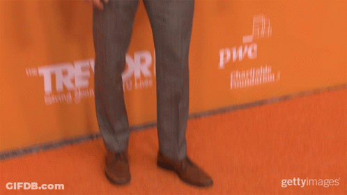 Man In Suit Standing In Front Of Revor Sign GIF