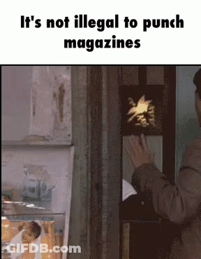 Man In Suit Standing In Front Of Sign It's Not Illegal To Punch Magazines GIF
