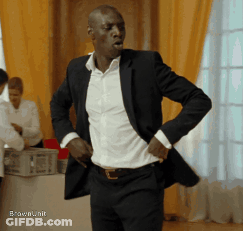 Man In Suit Standing In Front Of Table Saying Brownunit GIF