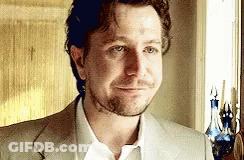 Man In Suit Standing In Front Of Window Smiling GIF