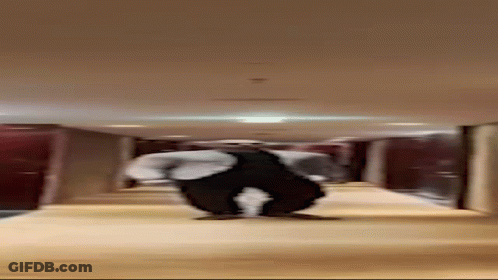 Man In Suit Standing In Hallway With Legs Crossed GIF
