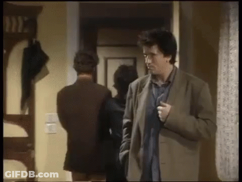 Man In Suit Standing In Hallway With Woman Behind Him GIF